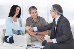 Insurance agent with couple shaking hands.