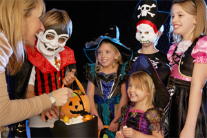 A group of children in Halloween costumes receiving candy.